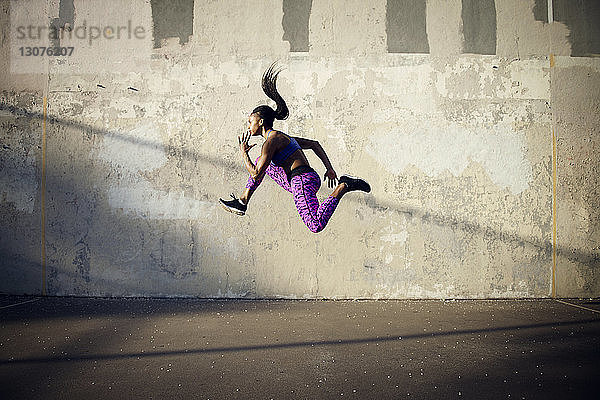 Seitenansicht einer Frau  die in der Luft gegen eine Wand springt
