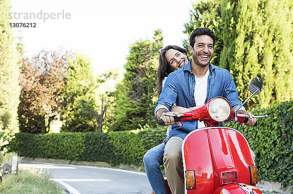 Glückliches Paar genießt Motorrollerfahrt im Park