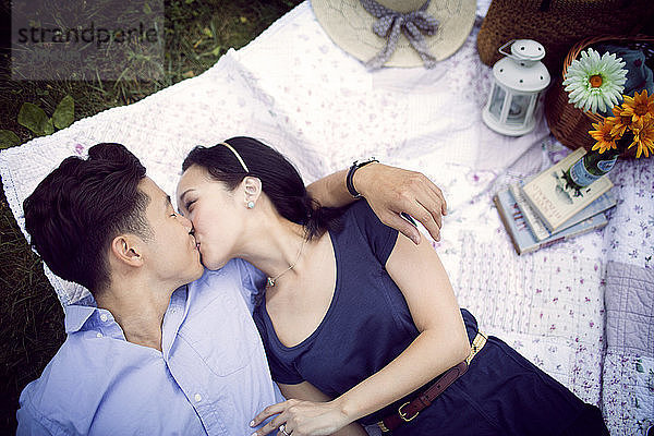 Draufsicht auf ein Paar  das sich küsst  während es auf dem Spielfeld im Park liegt