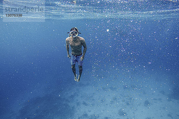 Porträt eines hemdlosen Mannes beim Schnorcheln unter Wasser