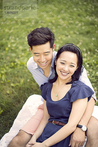 Hochwinkelansicht eines lächelnden Paares  das sich auf dem Feld entspannt