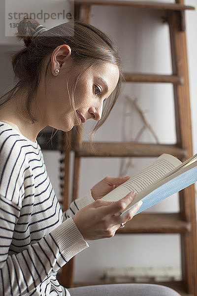 Nahaufnahme einer Frau  die zu Hause sitzt und ein Buch liest