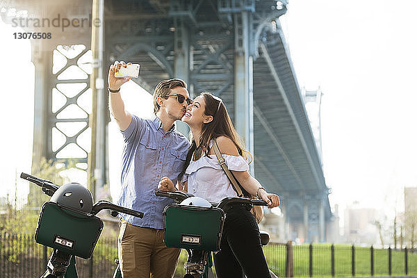 Pärchen küsst sich beim Selberfahren mit Fahrrädern gegen die Manhattan Bridge