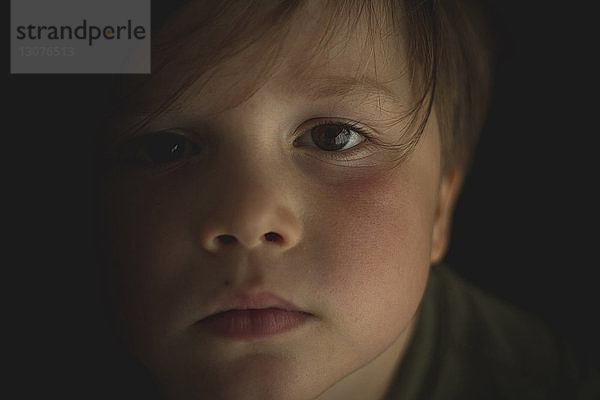 Nahaufnahme-Porträt eines süßen Jungen in einem dunklen Raum