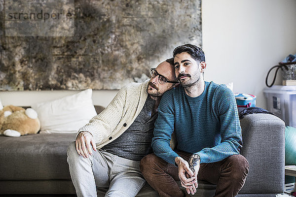 Liebevolles homosexuelles Paar sitzt zu Hause auf dem Sofa