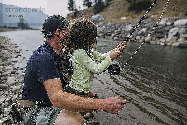 Seitenansicht von Vater und Tochter beim Angeln im Fluss im Yellowstone-Nationalpark