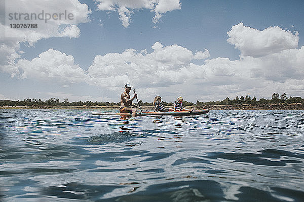 Vater paddelt mit Kindern im Fluss