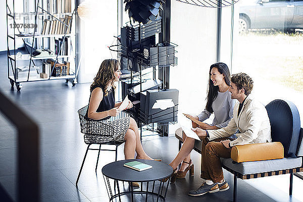 Hoher Blickwinkel auf glückliche Geschäftsleute  die im Büro auf dem Sofa sitzend diskutieren