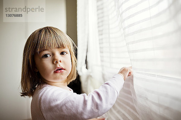 Seitenansicht Porträt eines niedlichen Mädchens am Fenster stehend