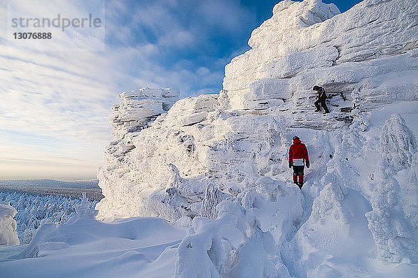 Freunde wandern auf schneebedecktem Berg gegen den Himmel