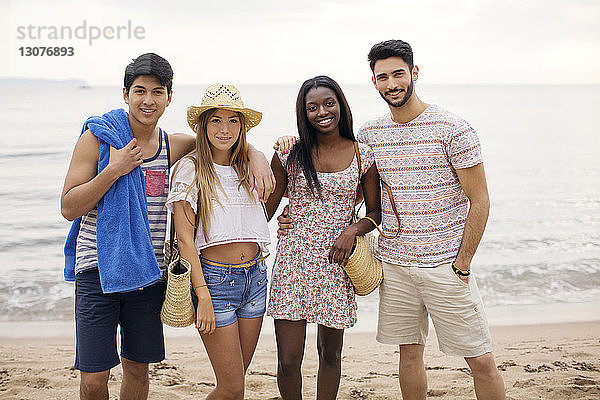 Porträt glücklicher multi-ethnischer Freunde am Strand stehend