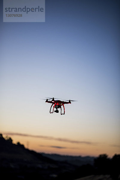 Niedrigwinkelansicht einer Drohne  die bei Sonnenuntergang gegen den Himmel fliegt