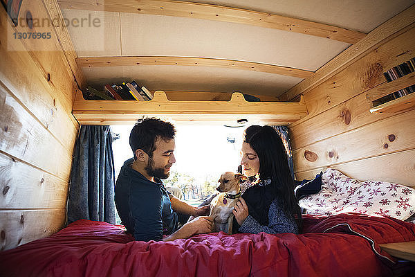 Paar sieht Hund an  während es sich im Bett im Wohnmobil entspannt