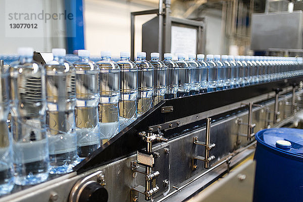 Nahaufnahme von Wasserflaschen in Reihe auf Lebensmittelverarbeitungsanlage in der Fabrik