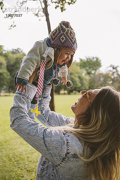 Glückliche Mutter hebt Tochter beim Spielen im Park