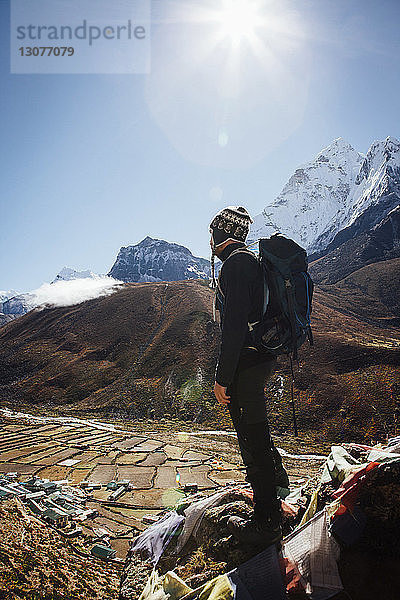 Wanderer mit Rucksack auf Berg stehend vor klarem blauen Himmel bei sonnigem Wetter