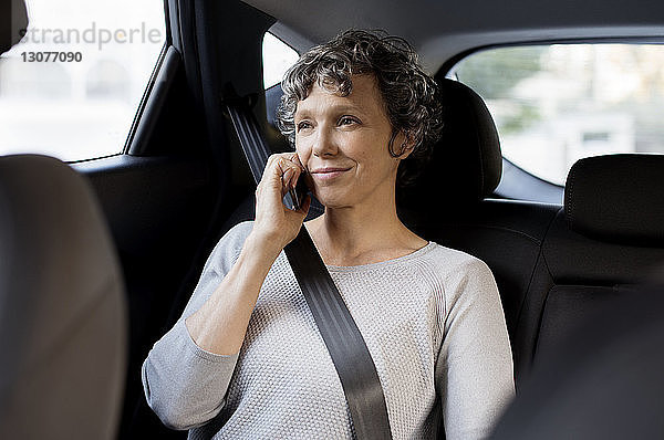 Reife Frau telefoniert im Auto sitzend per Handy