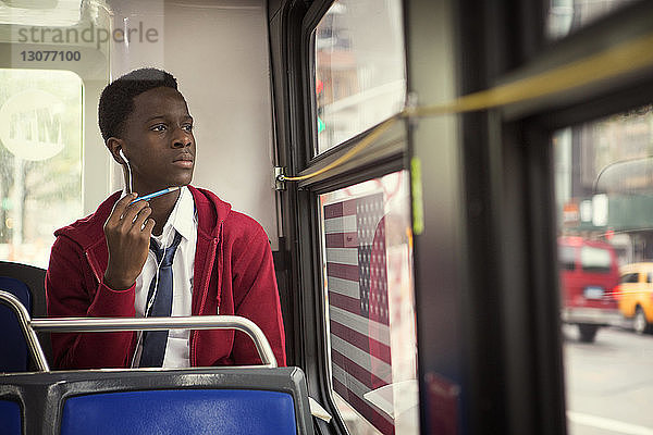 Nachdenklicher Student hört Musik  während er im Bus reist