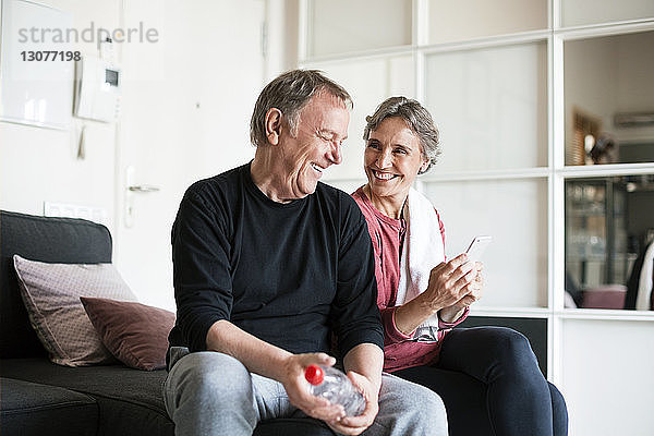 Glückliches älteres Ehepaar benutzt Smartphone im Wohnzimmer