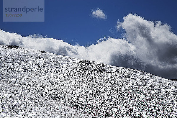 Nahaufnahme eines schneebedeckten Berges vor bewölktem Himmel