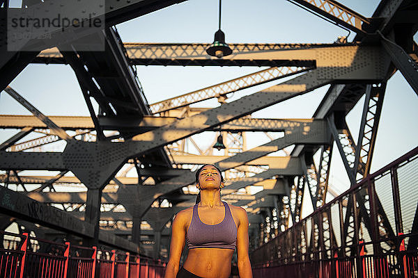 Frontansicht einer Frau  die sich entspannt  während sie auf der Brücke steht