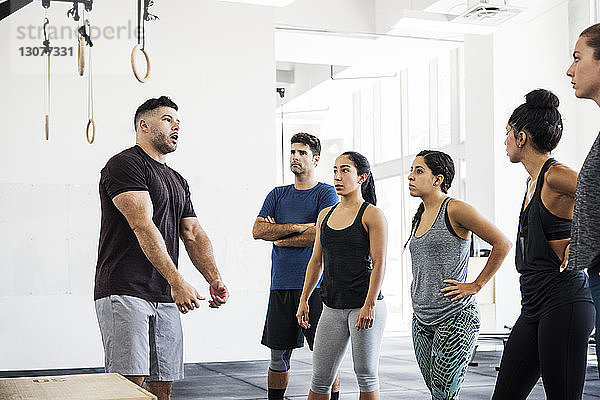 Athleten hören dem Ausbilder zu  der in der Crossfit-Turnhalle erklärt