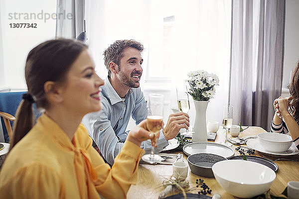 Glückliche Freunde trinken Champagner bei Tisch in einer Party