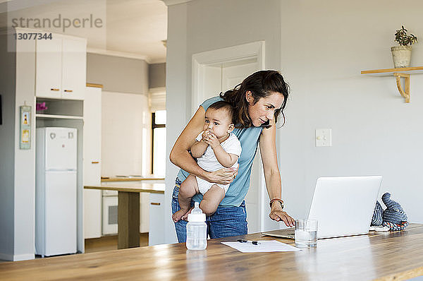 Frau benutzt Laptop-Computer  während sie mit ihrem Sohn zu Hause sitzt