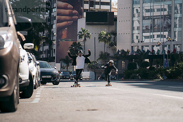 Männliche Freunde skateboarden bei Sonnenschein auf der Straße in der Stadt