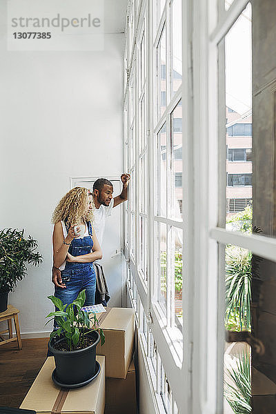 Ehepaar schaut durch Fenster  während es im neuen Haus steht
