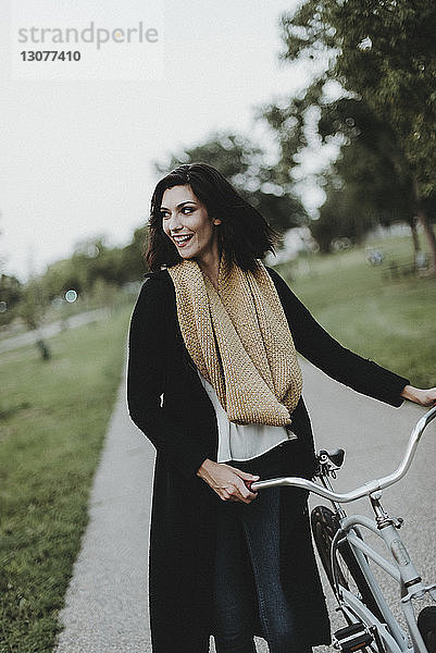 Fröhliche Frau mit Fahrrad im Park