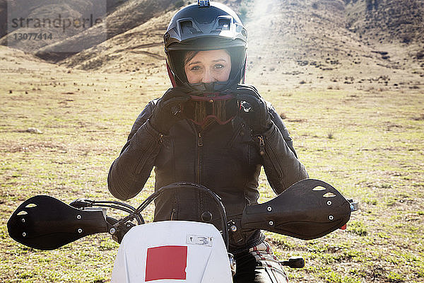 Porträt einer Motorradfahrerin  die auf einem Motorrad sitzt und eine Schutzbrille aufsetzt