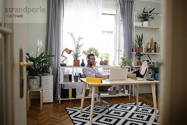 Entspannter Mann benutzt Laptop im Heimbüro