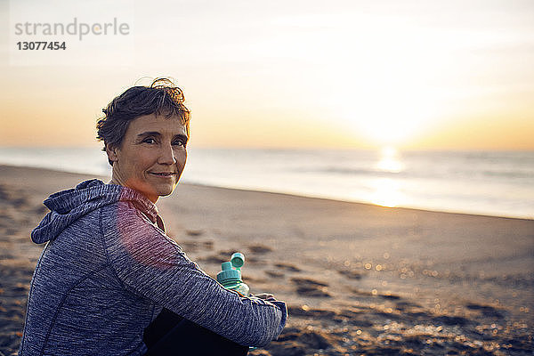 Porträt einer lächelnden älteren Frau  die sich am Strand ausruht