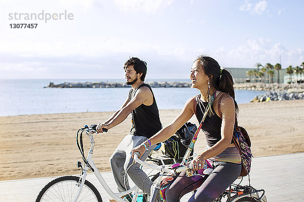 Sportliches Paar fährt Fahrrad auf der Straße am Strand