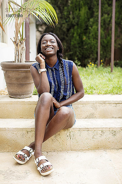 Porträt einer glücklichen Frau  die auf Stufen im Hof sitzt