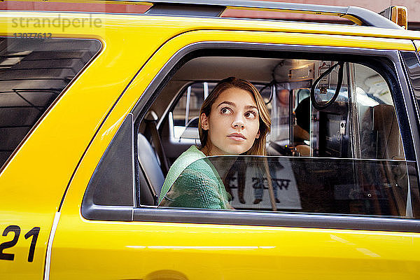 Frau schaut durch Fenster  während sie im Taxi in der Stadt sitzt