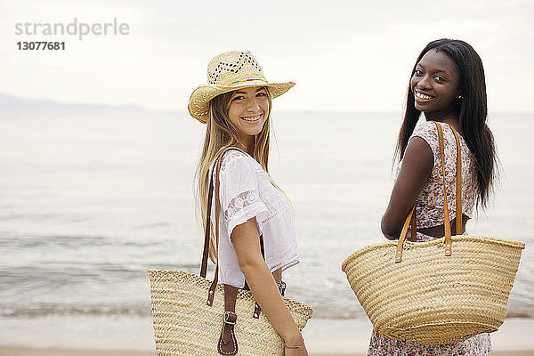 Seitenansicht Porträt von glücklichen Freundinnen  die am Strand am Ufer stehen