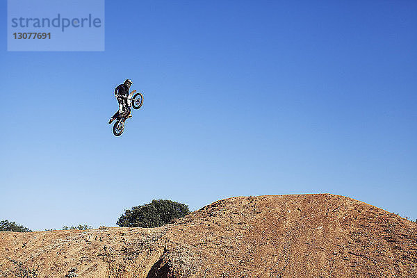 Niedrigwinkelansicht eines Bikers  der einen Stunt vor klarem  blauem Himmel macht