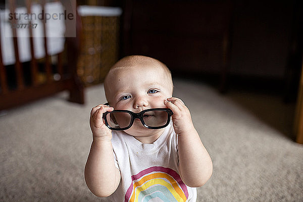 Hochwinkelporträt eines Mädchens mit Brille  das zu Hause sitzt