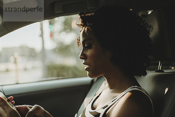 Nahaufnahme einer Frau  die ein Smartphone benutzt  während sie im Auto sitzt