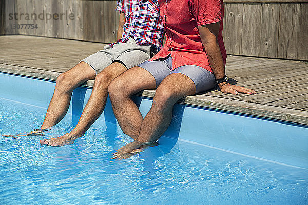 Niedriger Teil eines homosexuellen Paares entspannt sich am Pool