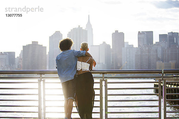 Rückansicht eines am Geländer stehenden Paares in der Stadt an einem sonnigen Tag