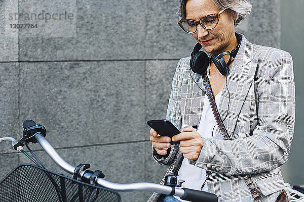 Frau mit Smartphone an der Wand