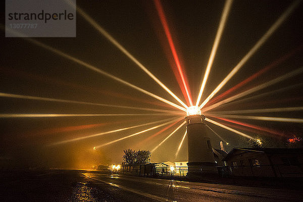 Lichtstrahlen  die vom Leuchtturm nachts auf dem Meer ausstrahlen