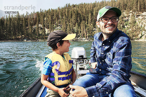 Glückliche Vater und Sohn reisen in einem Motorboot auf dem See