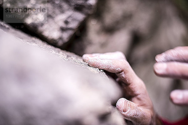 Nahaufnahme von kupierten Händen  die beim Bouldern am Fels zupacken