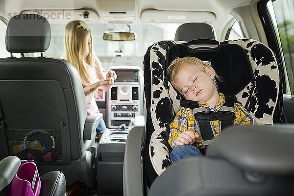 Bruder schläft  während die Schwester im Auto spielt