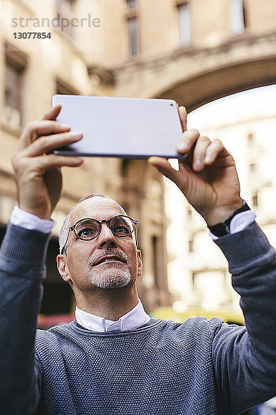 Mann fotografiert mit Tablet-Computer in der Stadt