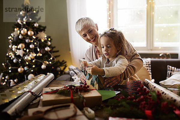 Mädchen und Großmutter packen zu Weihnachten Geschenke bei Tisch